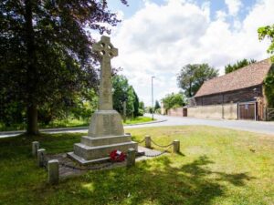 Image of Shepreth war memorial with a poppy wreath on it.