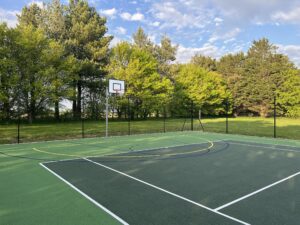 Photo of a multi use tennis court in the sunshine with trees behind.