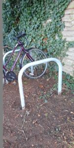 A bicycle leaning on a bike rack. Another empty bike rack is in the foreground.